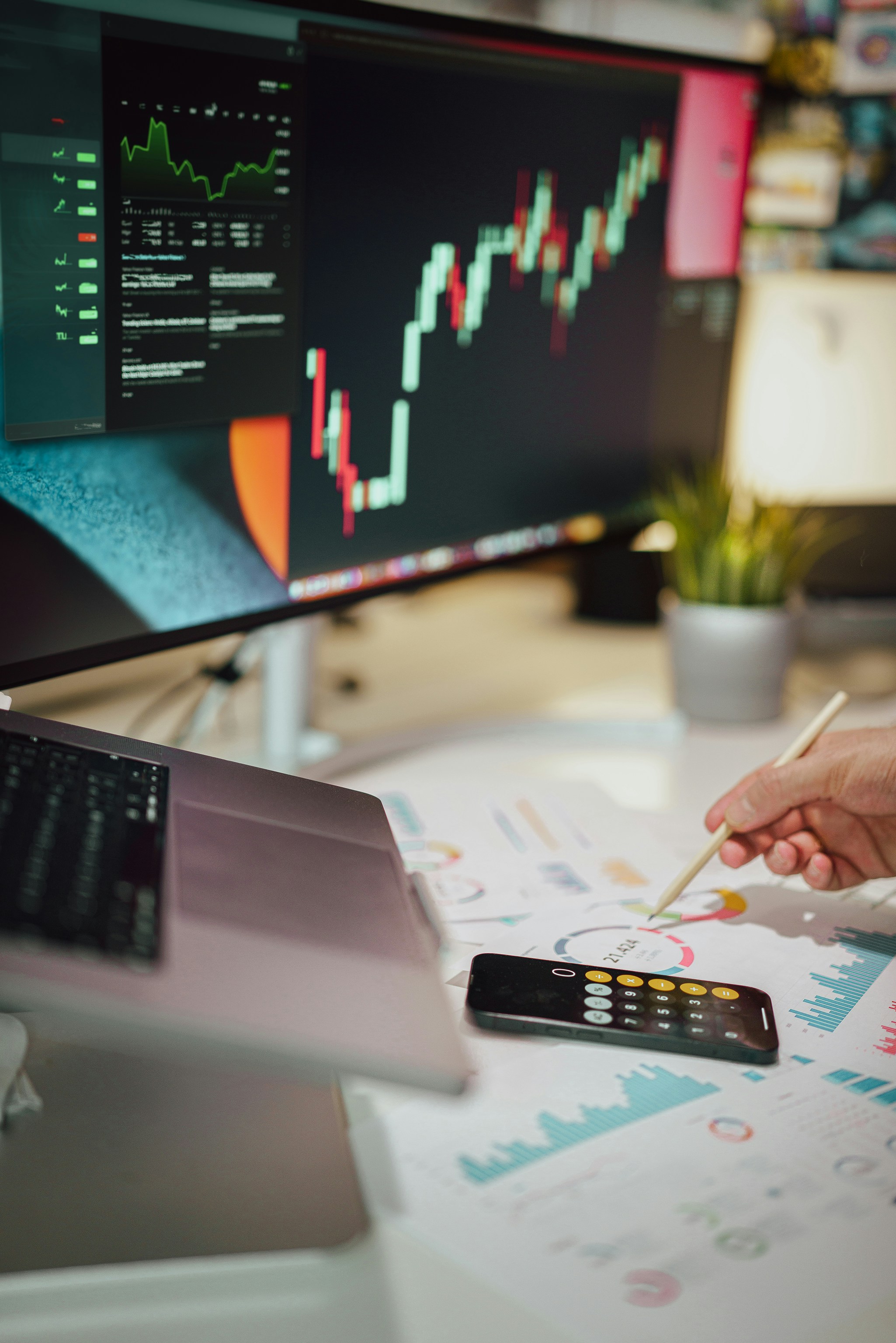 A quiet trading workspace with a monitor showing market charts and reports laid out on the desk